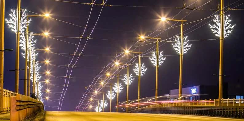 Tramvay hattı üzerindeki direklere sıra sıra kurulmuş beyaz ışıklı orta boy dal ağaçları