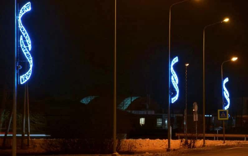 Cadde direklerinde sıralı mavi ve altın LED S-kıvrımlı şerit motifler, kar yağışlı gece