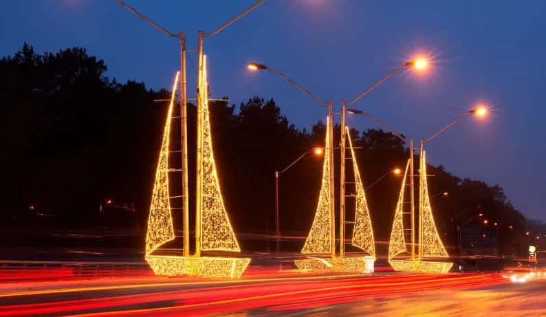 Şehir içi yolda direklere yaslanmış üç adet altın sarısı LED yelkenli tekne motifi