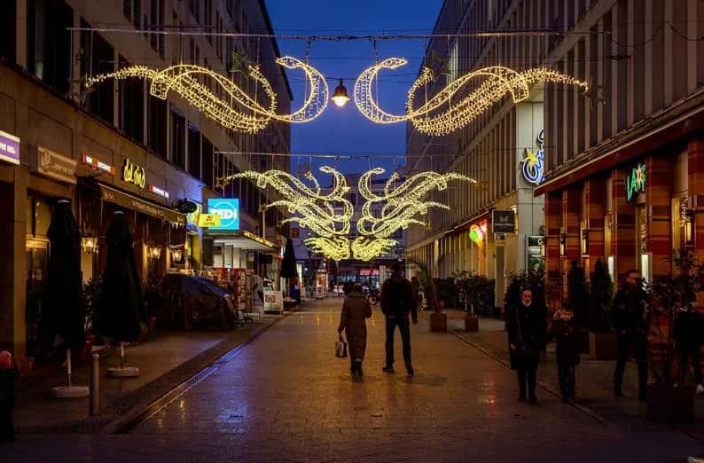 Dar tarihi sokakta cepheden cepheye gerilmiş altın kıvrımlı sarkıtlar, iki kat halinde