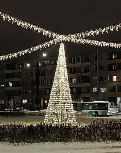 Meydanda saçak ışıkları altında dev koni formlu ışık ağacı, apartmanlar önünde