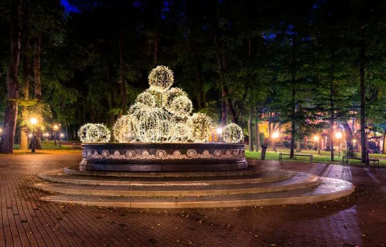Park ortasındaki taş havuz üzerine kurulu sıcak beyaz ışık topu piramidi