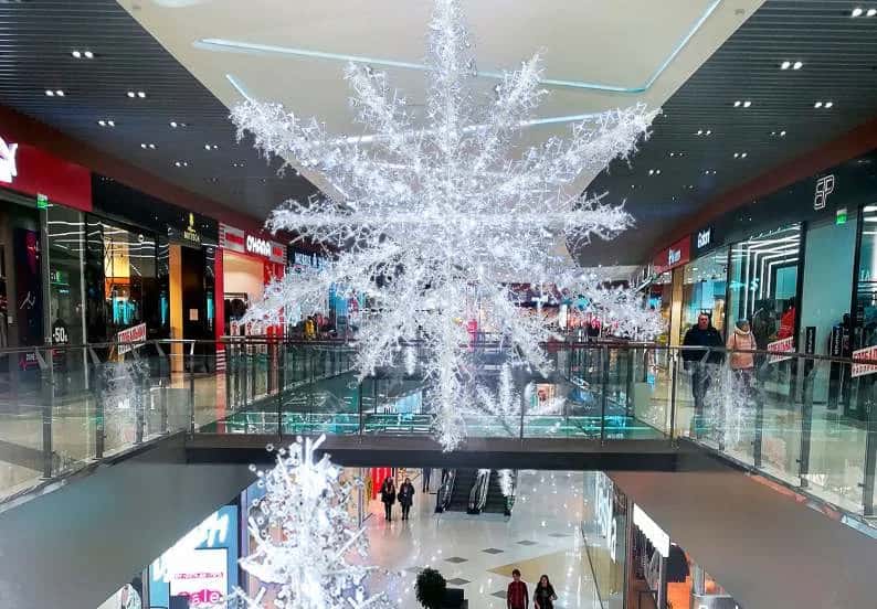 AVM atriumunun tavanından sarkan dev beyaz kar tanesi figürü, iki kat arası boşlukta