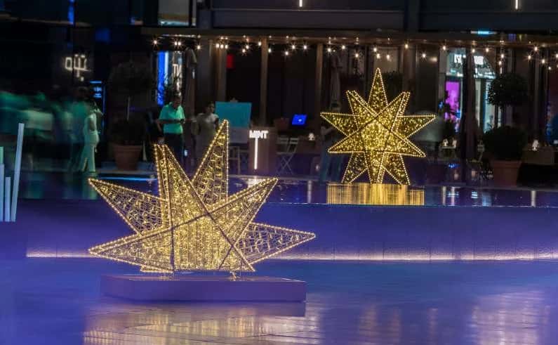 AVM önü meydanında iki adet altın sarısı ışıklı dev yıldız figürü, gece